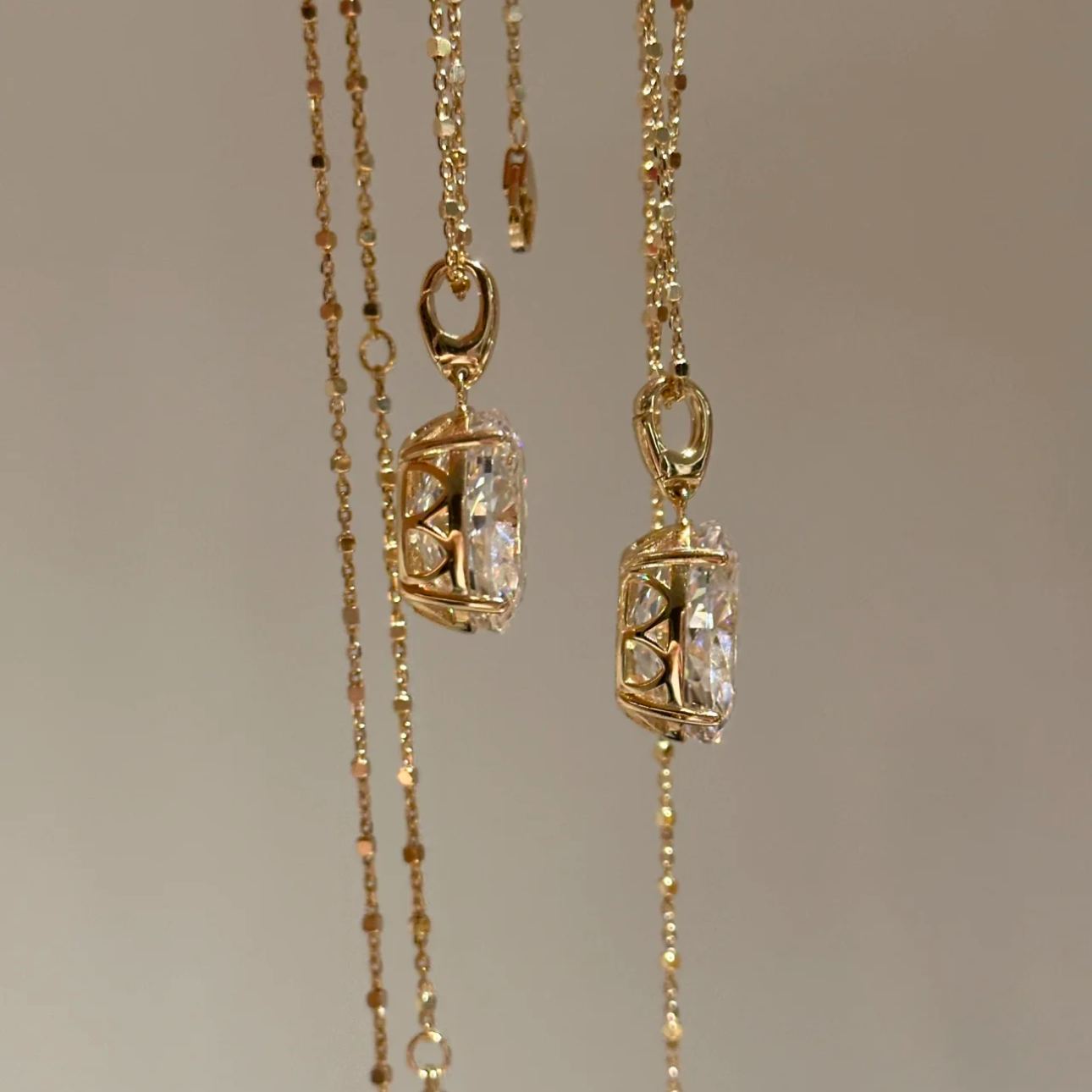 Close-up of two 10 carat oval cut solitaire pendants in silver and rose gold, showcasing the intricate and secure basket setting.