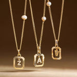 A 14K gold plated vintage pearl initial necklace resting elegantly on soft, textured white fabric.
