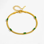 Angled view of a 14K gold plated snake chain bracelet featuring five green baguette-cut cubic zirconia stones, a lobster clasp, and an extender chain, isolated on a clean white background.
