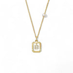 A 14K gold plated vintage rectangular sunburst pendant featuring a dancing pave initial letter B and a side freshwater pearl, isolated on a white background.