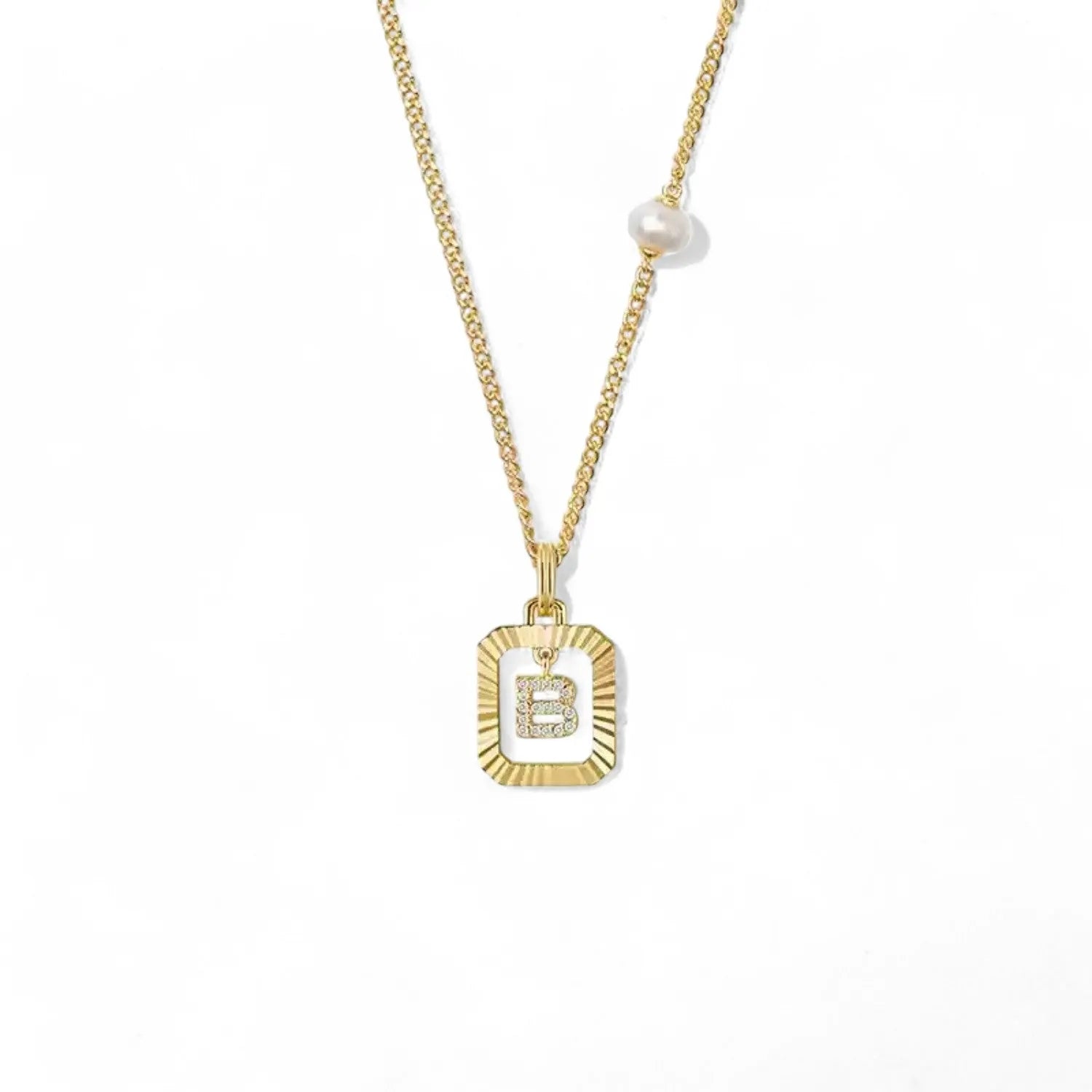 A 14K gold plated vintage rectangular sunburst pendant featuring a dancing pave initial letter B and a side freshwater pearl, isolated on a white background.