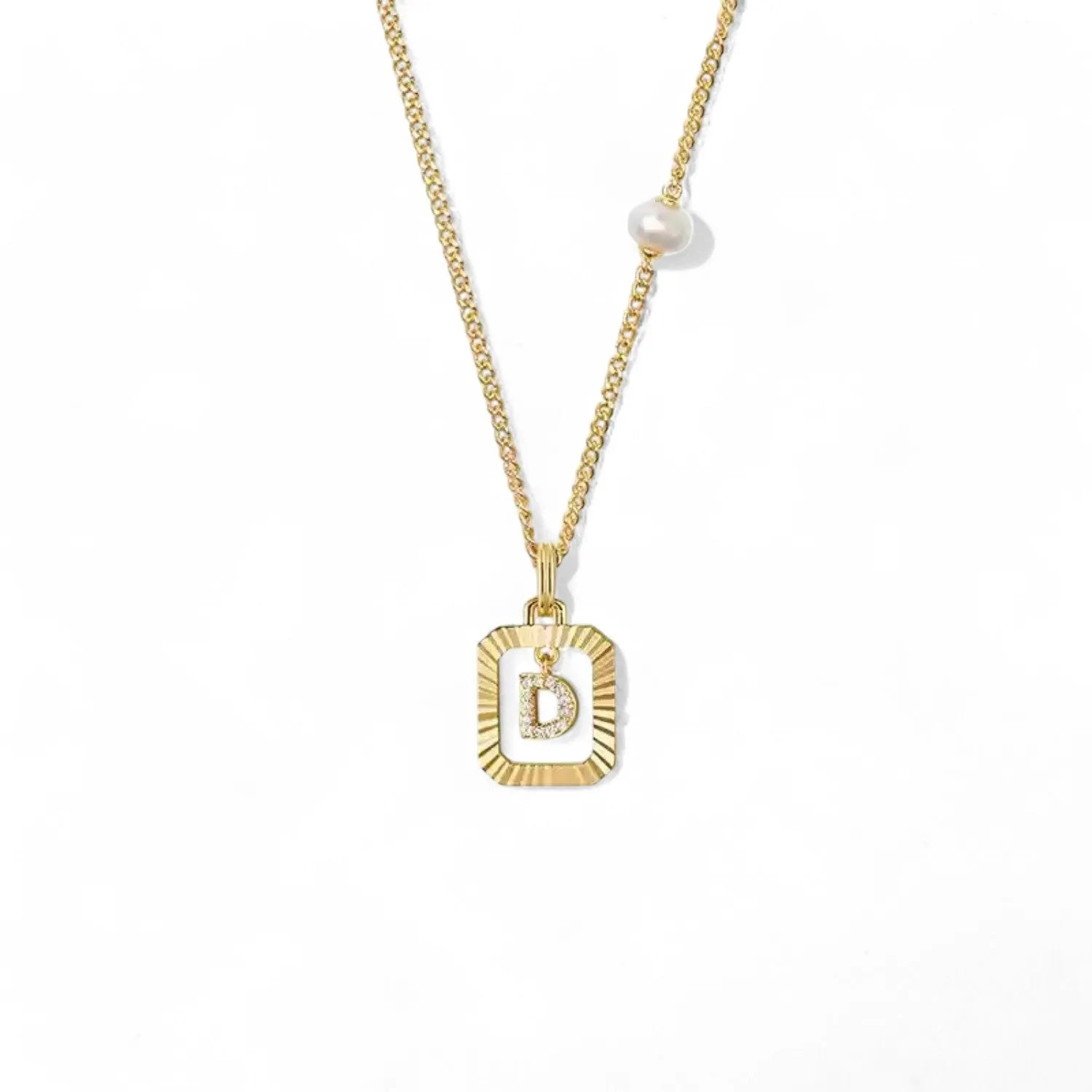 A 14K gold plated vintage rectangular sunburst pendant featuring a dancing pave initial letter D and a side freshwater pearl, isolated on a white background.