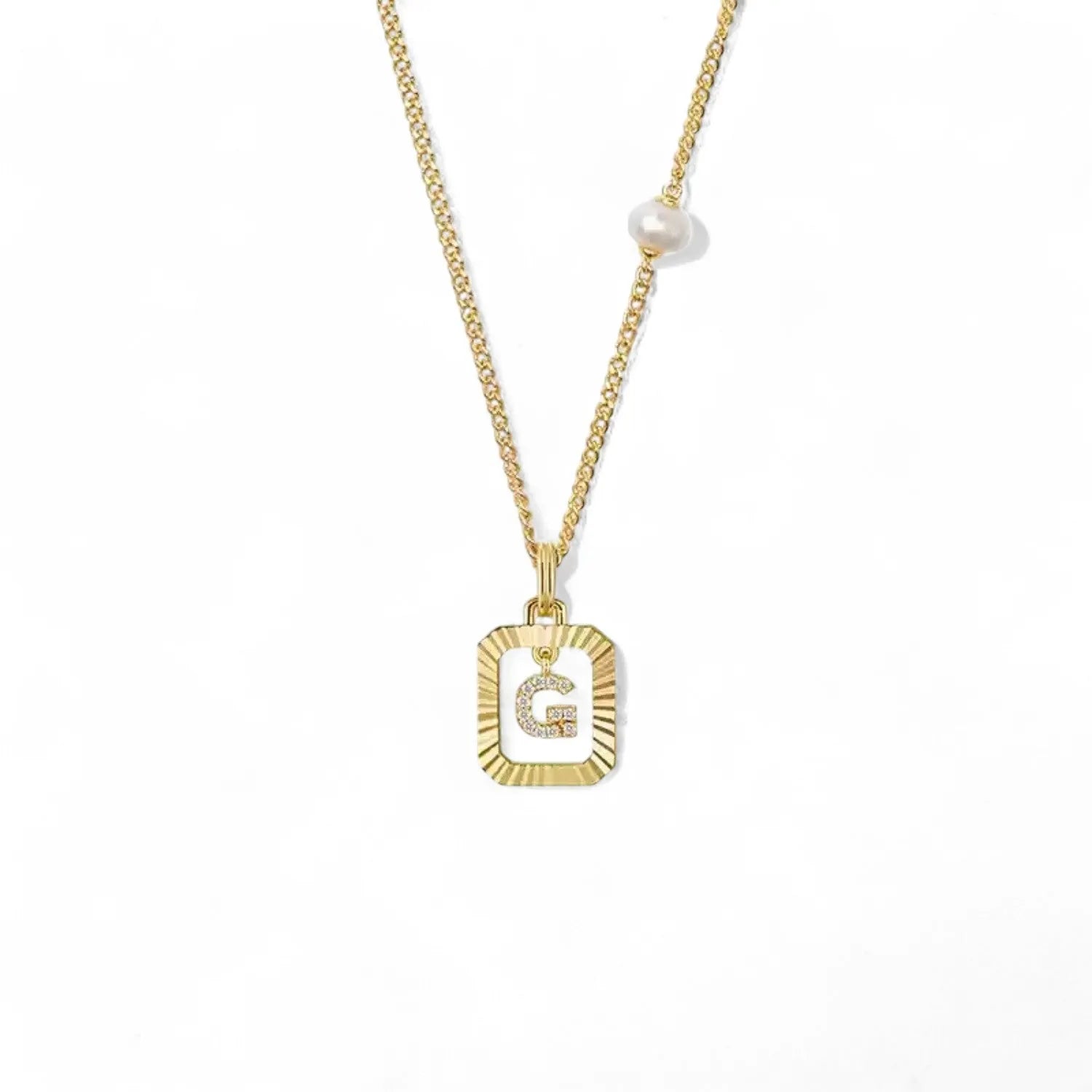 A 14K gold plated vintage rectangular sunburst pendant featuring a dancing pave initial letter G and a side freshwater pearl, isolated on a white background.