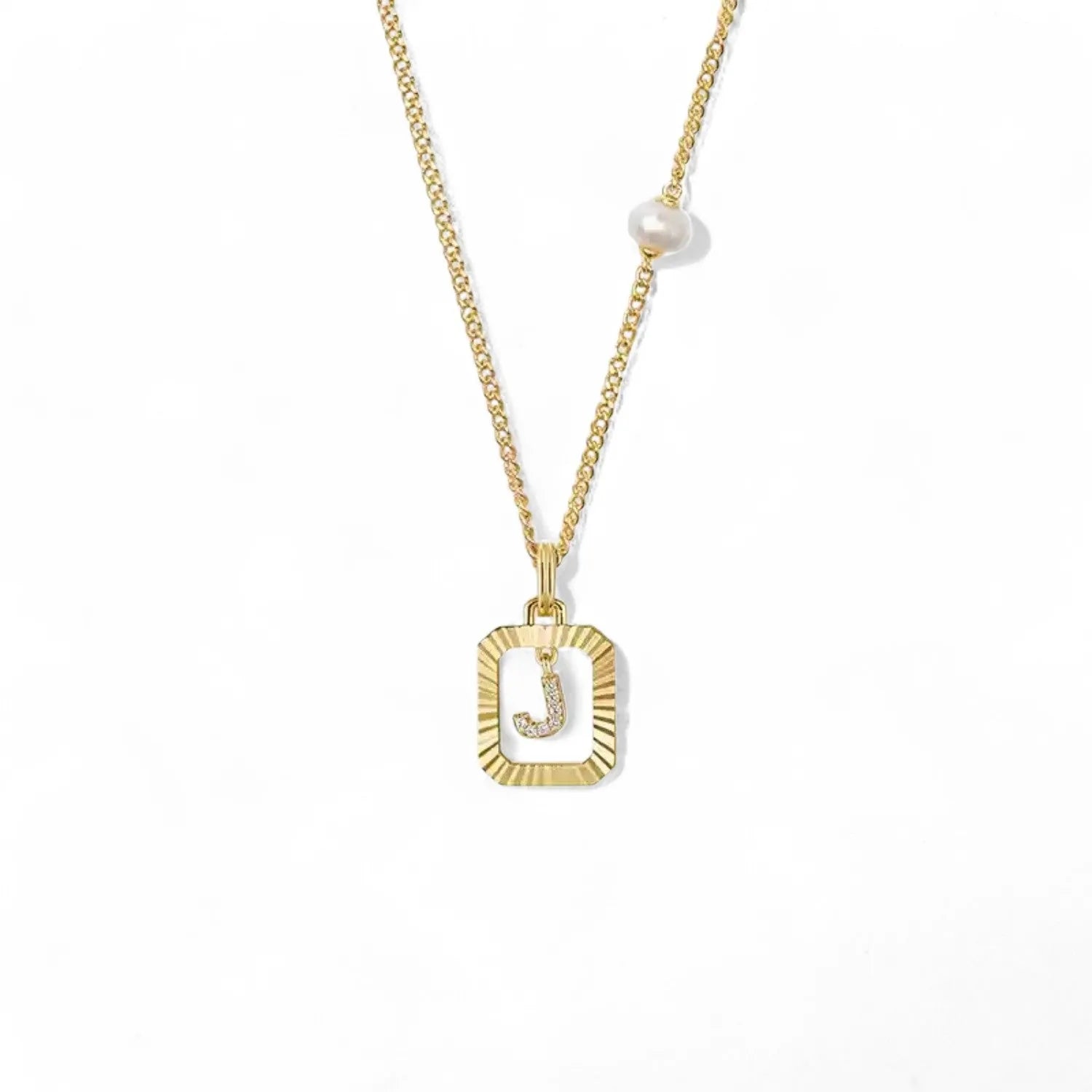 A 14K gold plated vintage rectangular sunburst pendant featuring a dancing pave initial letter J and a side freshwater pearl, isolated on a white background.