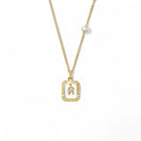 A 14K gold plated vintage rectangular sunburst pendant featuring a dancing pave initial letter K and a side freshwater pearl, isolated on a white background.