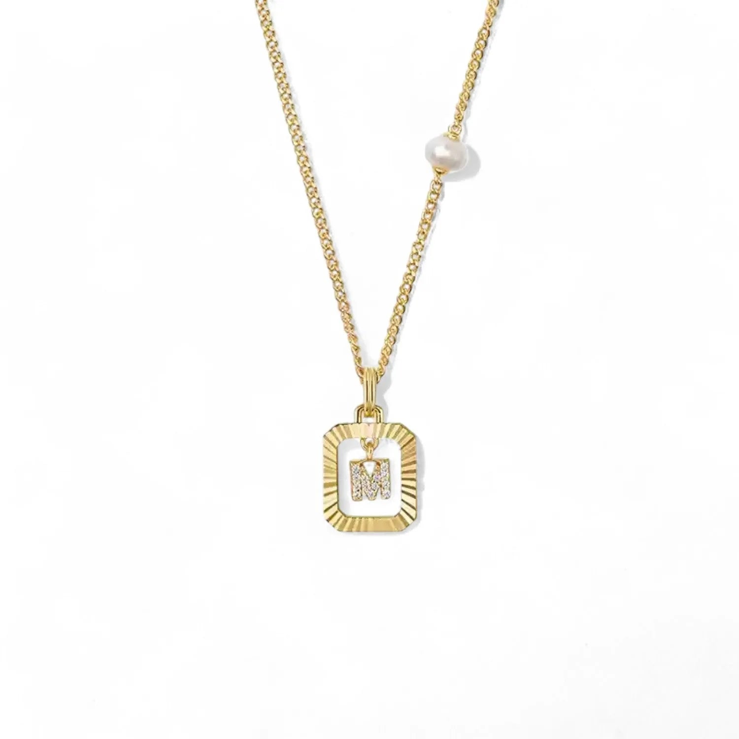 A 14K gold plated vintage rectangular sunburst pendant featuring a dancing pave initial letter M and a side freshwater pearl, isolated on a white background.