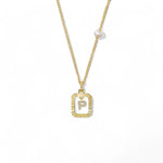 A 14K gold plated vintage rectangular sunburst pendant featuring a dancing pave initial letter P and a side freshwater pearl, isolated on a white background.