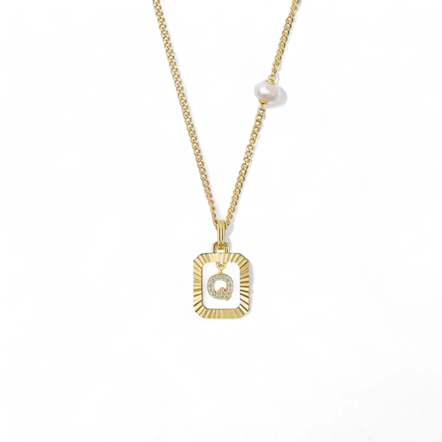 A 14K gold plated vintage rectangular sunburst pendant featuring a dancing pave initial letter Q and a side freshwater pearl, isolated on a white background.