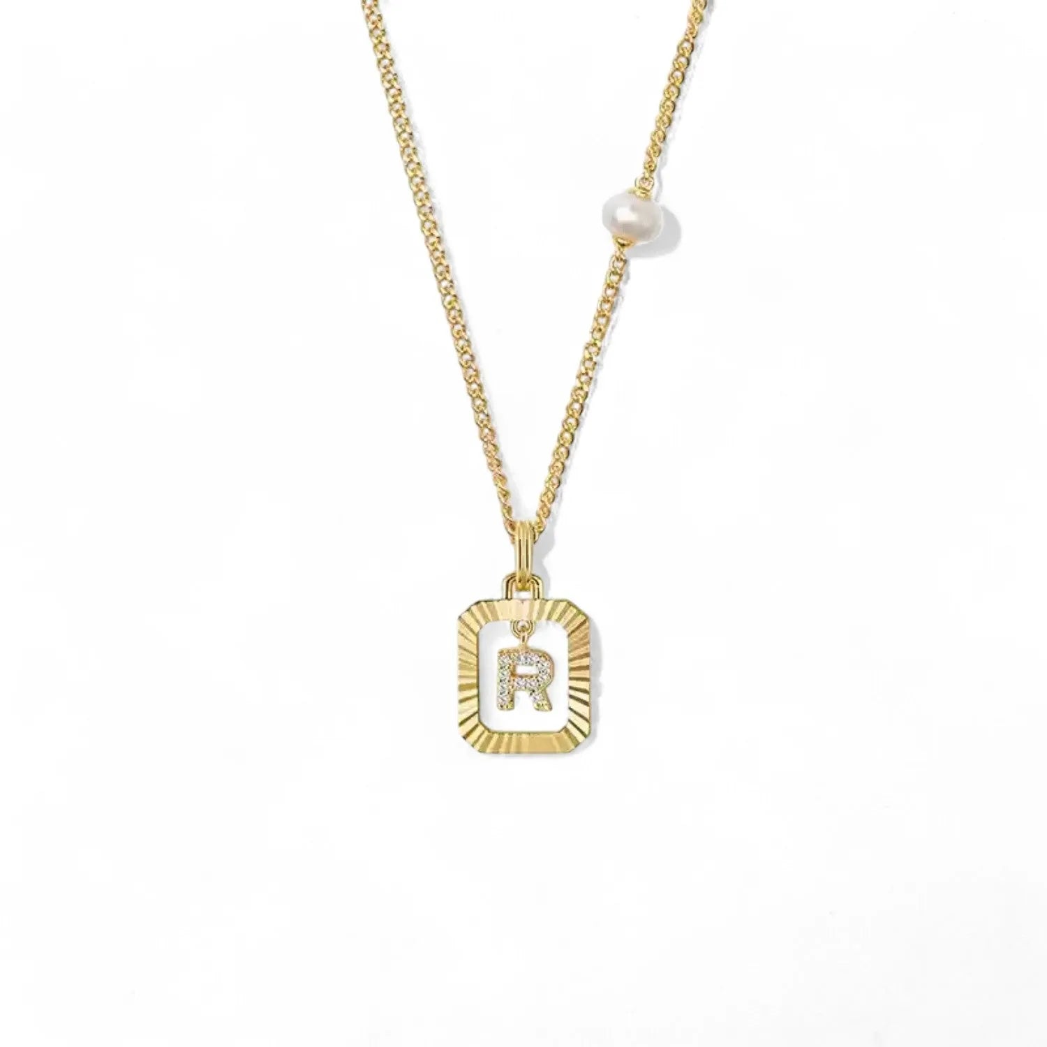 A 14K gold plated vintage rectangular sunburst pendant featuring a dancing pave initial letter R and a side freshwater pearl, isolated on a white background.
