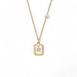 A 14K gold plated vintage rectangular sunburst pendant featuring a dancing pave initial letter R and a side freshwater pearl, isolated on a white background.