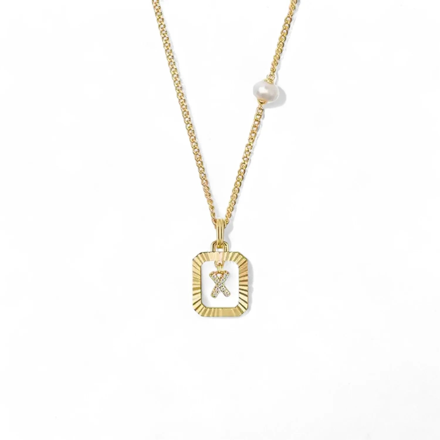 A 14K gold plated vintage rectangular sunburst pendant featuring a dancing pave initial letter X and a side freshwater pearl, isolated on a white background.