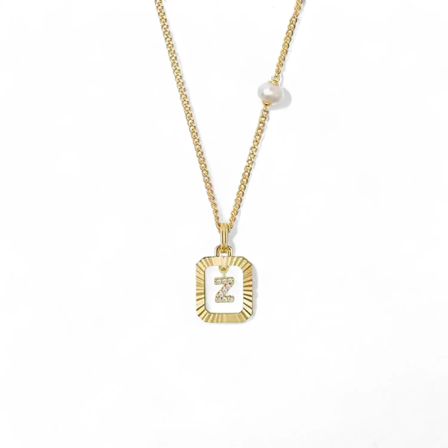 A 14K gold plated vintage rectangular sunburst pendant featuring a dancing pave initial letter Z and a side freshwater pearl, isolated on a white background.
