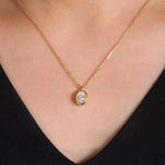 A model wearing the minimalist 18K solid gold oval bezel diamond necklace resting gracefully on the chest.