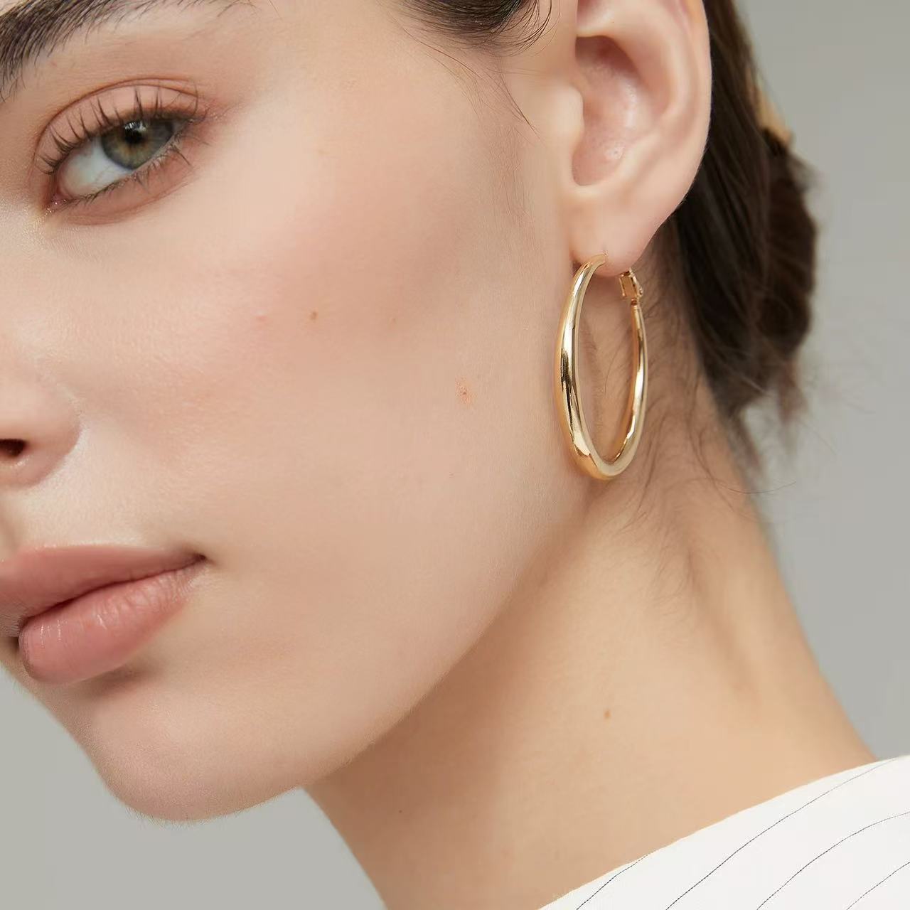 Close-up profile view of the polished chunky gold hoop earrings reflecting soft natural light.