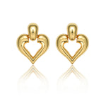 A pair of polished 18K gold plated chunky stud earrings featuring a dome top and an openwork heart design, displayed with a reflection on a clean white background.