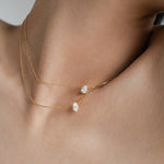 Front view of a model wearing an adjustable 18k gold layered necklace set, highlighting the perfect spacing between the oval and teardrop pendants.