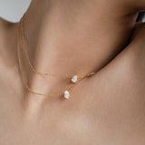 Front view of a model wearing an adjustable 18k gold layered necklace set, highlighting the perfect spacing between the oval and teardrop pendants.