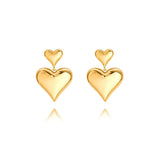 A pair of 18K gold plated drop earrings featuring a smaller heart stud cascading into a larger 3D puffy heart, isolated on a white background.