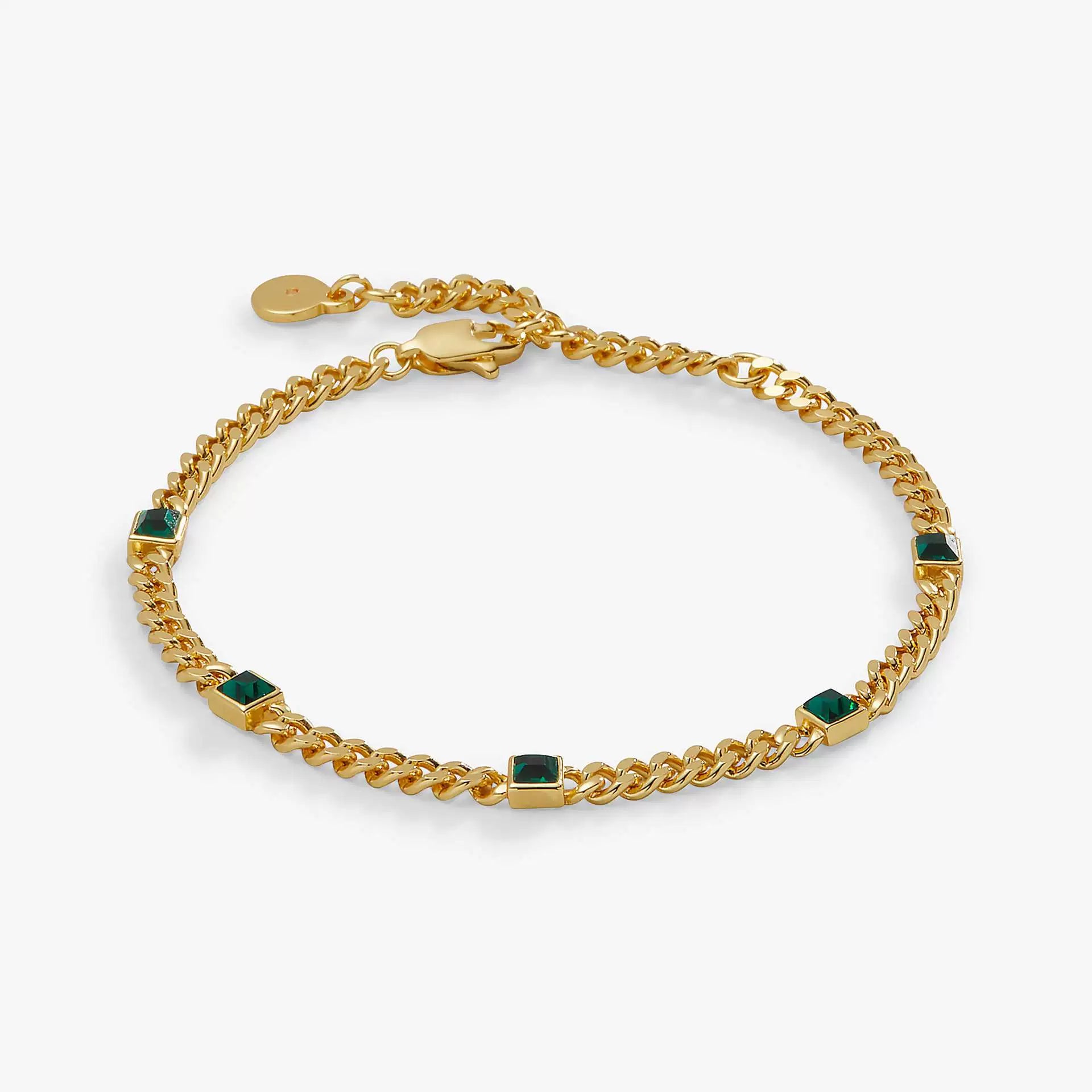 An 18K gold plated curb link chain bracelet featuring square-cut emerald green stones evenly stationed, complete with a lobster clasp and extender, isolated on a white background.