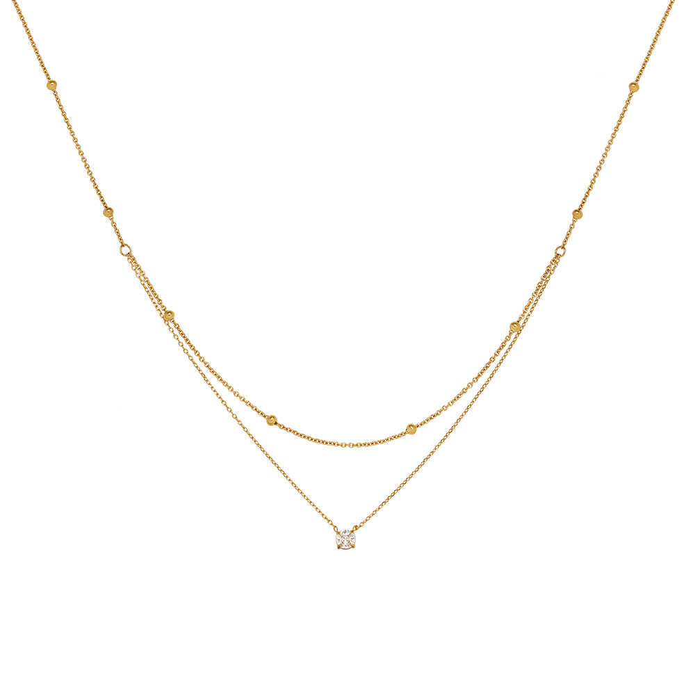 A delicate 18K gold plated double layered necklace featuring a top beaded satellite chain and a bottom chain with a single 4mm round clear CZ pendant, isolated on a clean white background.