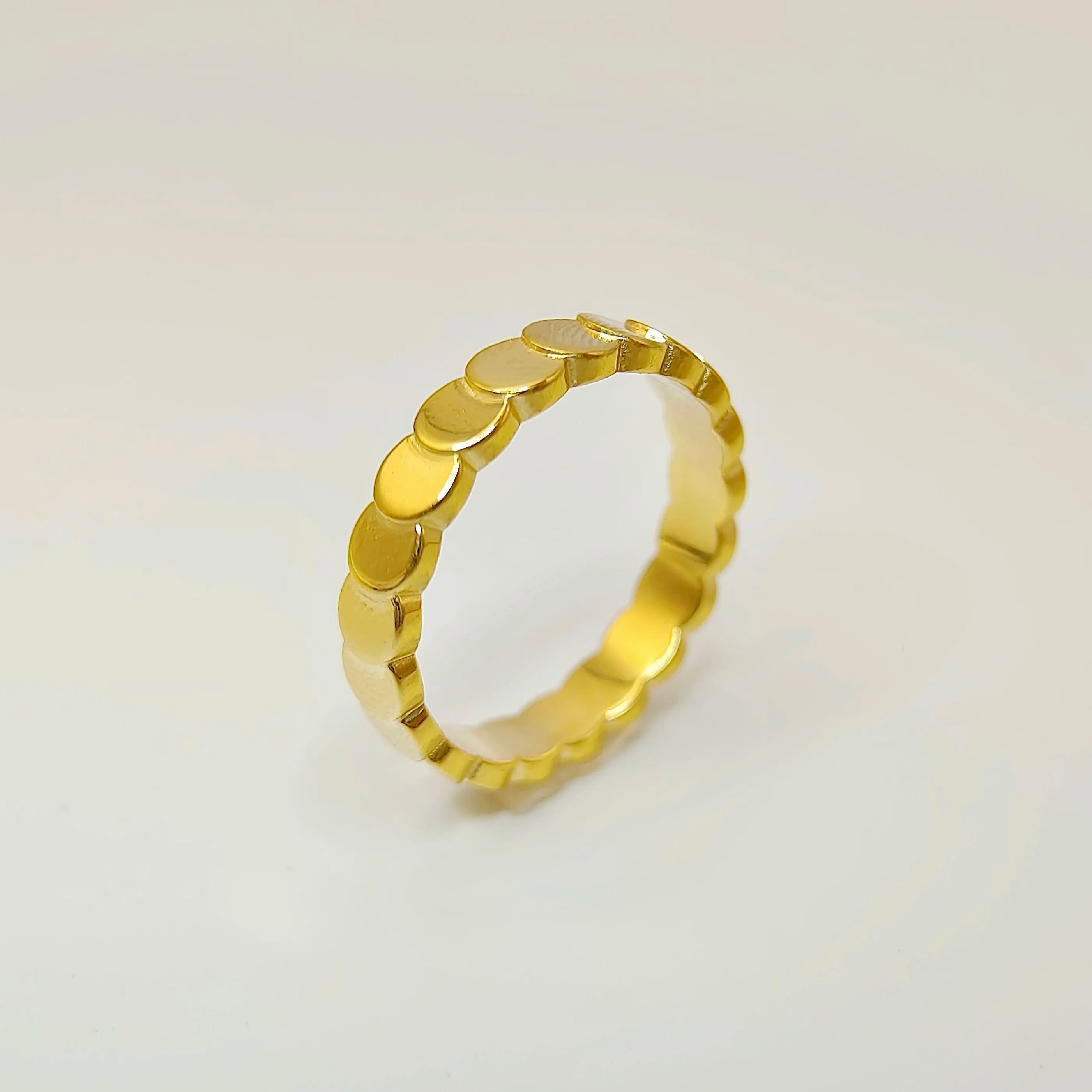 Close-up studio shot of an 18k gold overlapping disc ring standing upright against a crisp white background.
