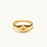 Front view of a dainty gold-plated signet ring with a deeply engraved eight-point starburst motif and no center stone, on a white background.