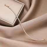 A gold diamond tennis bracelet elegantly draped over a luxury jewelry gift box, highlighting its brilliant sparkle.