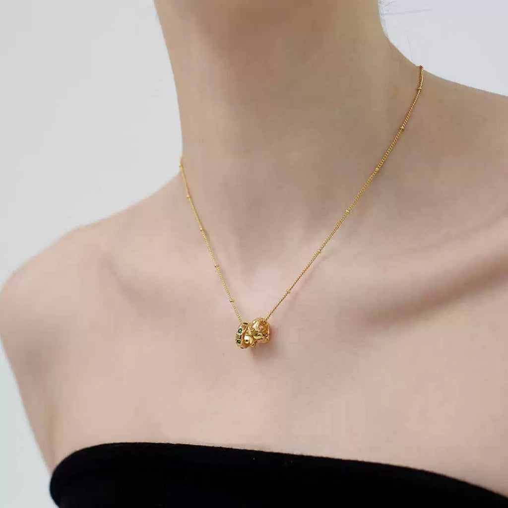 Side-angle lifestyle shot of a woman wearing the gold trio bead pendant on a dainty beaded satellite chain.
