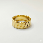 A chunky 18K gold band ring featuring a diagonal ribbed texture and a smooth interior, displayed against a seamless white background.