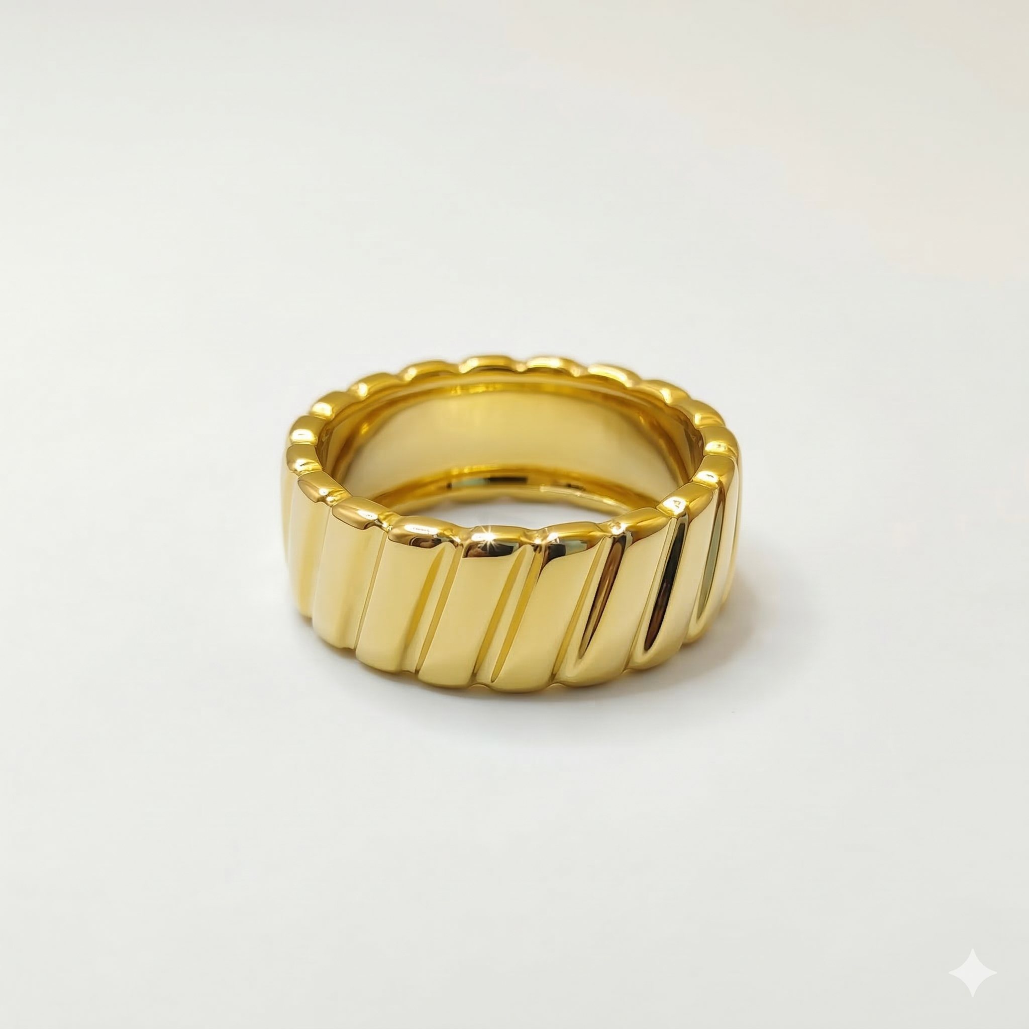 A chunky 18K gold band ring featuring a diagonal ribbed texture and a smooth interior, displayed against a seamless white background.