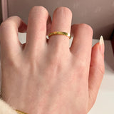 Close-up of an 18k gold stackable coin ring worn on a woman's index finger, highlighting the scalloped edges.