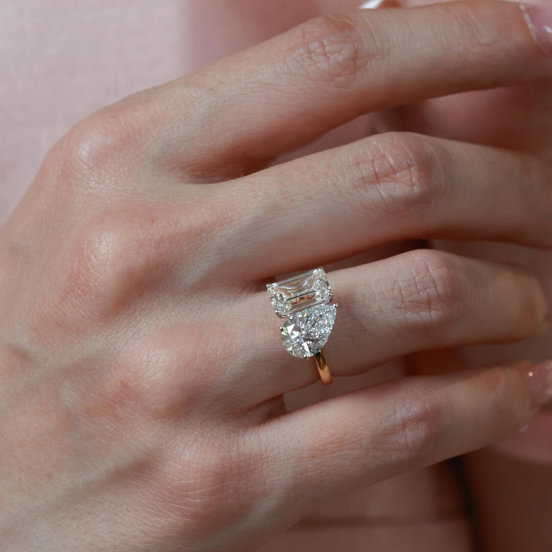 Close-up of the Twin Aura ring showcasing the icy-white DE color and VS clarity of the emerald and pear diamonds.