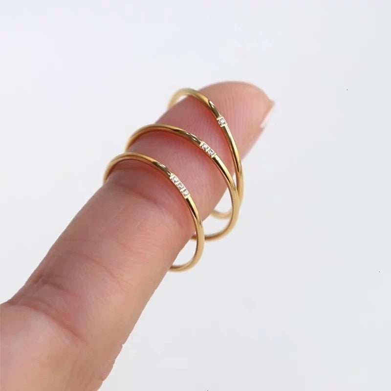 A model's hand showcasing the 3-piece gold stacking ring set worn together on a single finger for a bold, layered look.