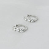A pair of premium 925 sterling silver huggie hoop earrings featuring three brilliant-cut stones, isolated on a white background.
