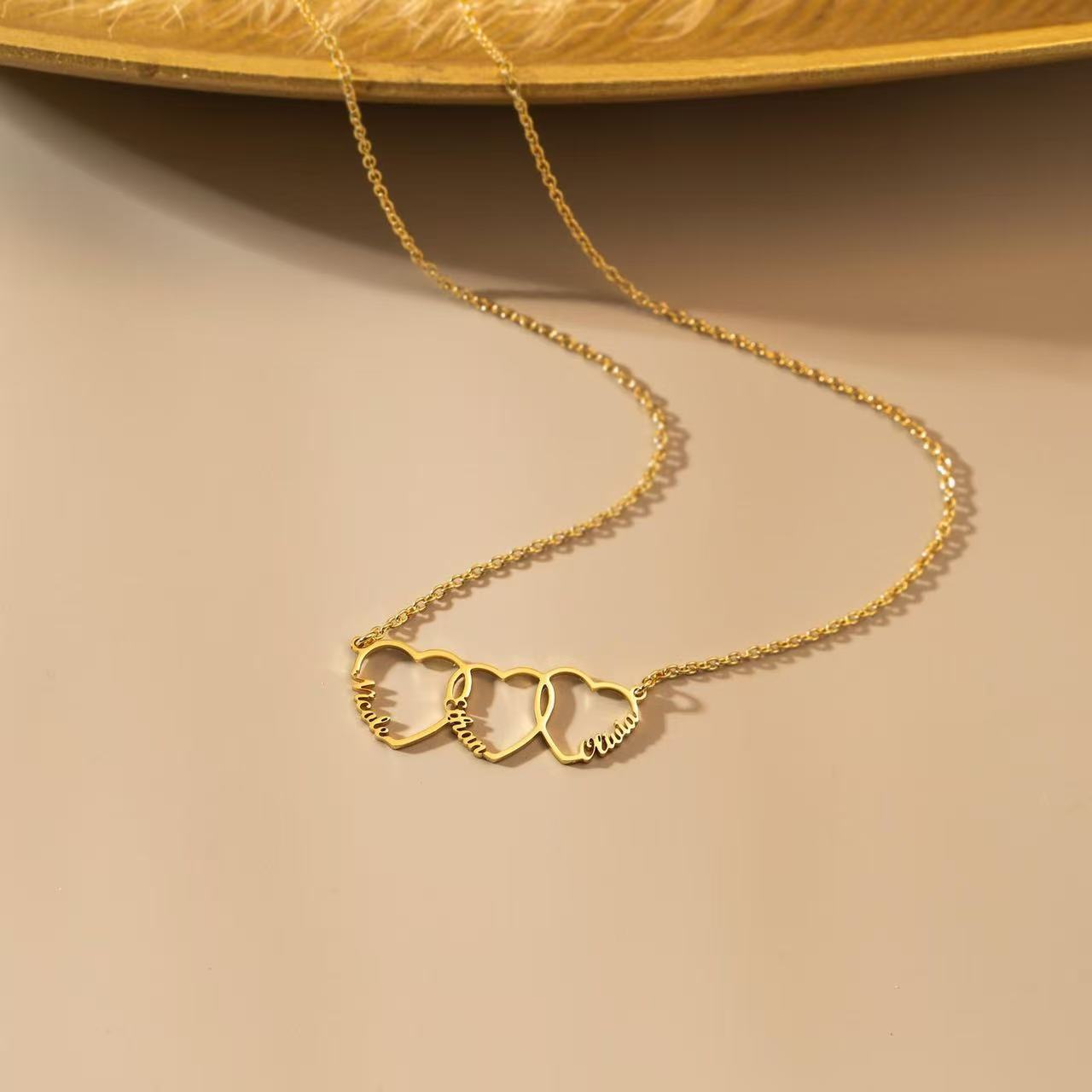 Gold necklace with heart-shaped pendants on a beige background