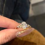 A hand holding the 18K gold Shooting Star Spark ring, showcasing the light-catching shared-prong halo setting.