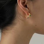Gold earring with colorful stones worn by a person