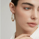 Close-up profile view of the polished chunky gold hoop earrings reflecting soft natural light.