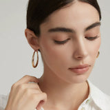 Close-up profile view of the polished chunky gold hoop earrings reflecting soft natural light.