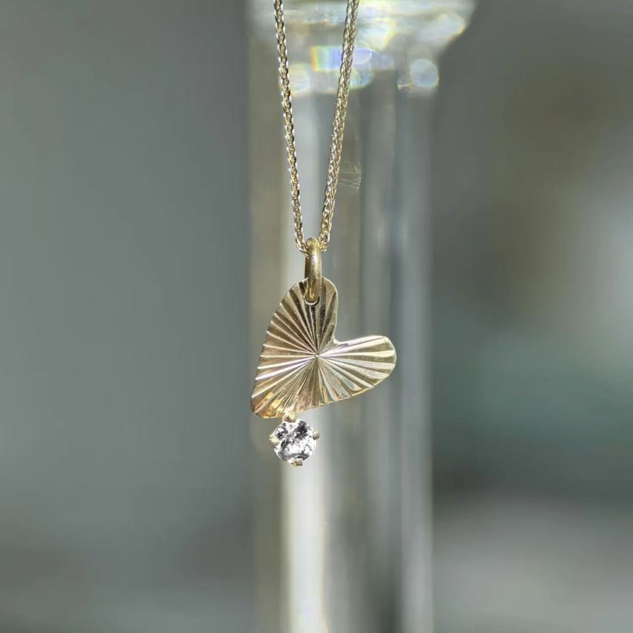 Gold necklace with a leaf-shaped pendant on a blurred background