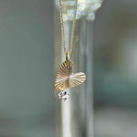 Gold necklace with a leaf-shaped pendant on a blurred background