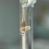 Gold necklace with a leaf-shaped pendant on a blurred background