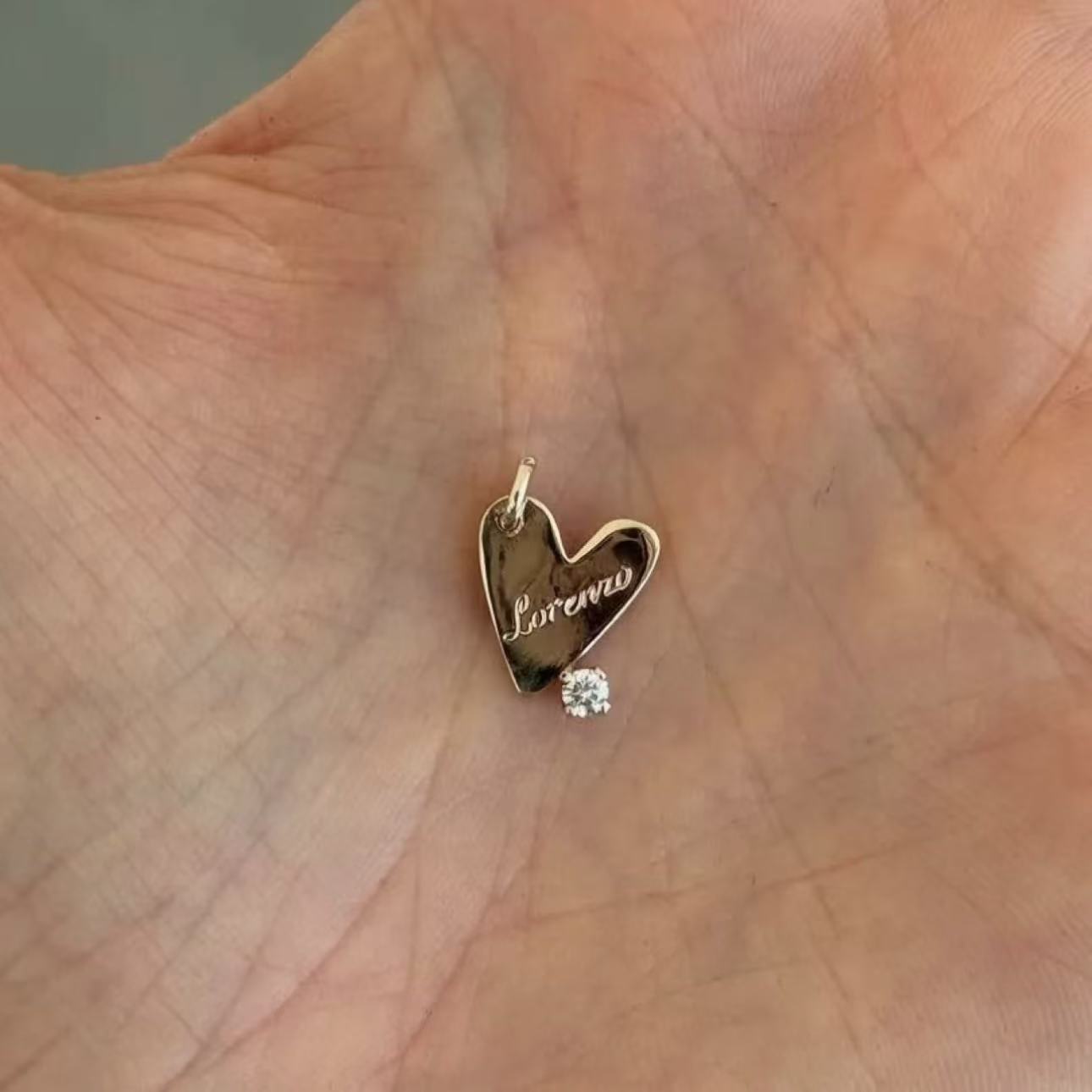 Heart-shaped pendant with 'Loraine' engraving on a hand