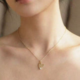 Gold necklace with a heart-shaped pendant on a person's neck