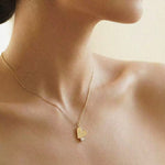 Gold necklace with a heart-shaped pendant on a person's neck