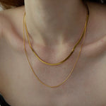 Close-up of the liquid metal shine on the layered gold Snake Chain Duo Necklace draped gracefully over the collarbone