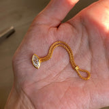 Gold ring with a marquise-shaped pendant held in a hand.