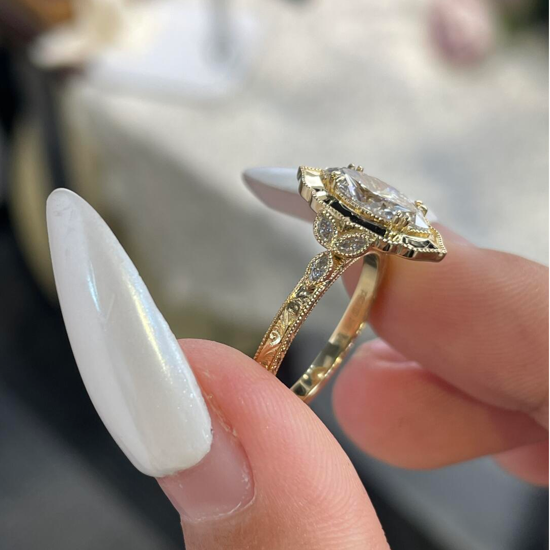 Detailed view of the E-F color VVS2 marquise center stone surrounded by a scalloped halo on a warm gold setting.
