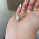 Detailed view of the E-F color VVS2 marquise center stone surrounded by a scalloped halo on a warm gold setting.