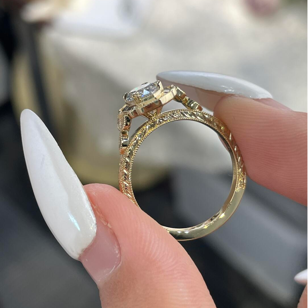Close-up side profile of the marquise diamond ring highlighting the intricate vintage floral engravings and milgrain details on the gold band.